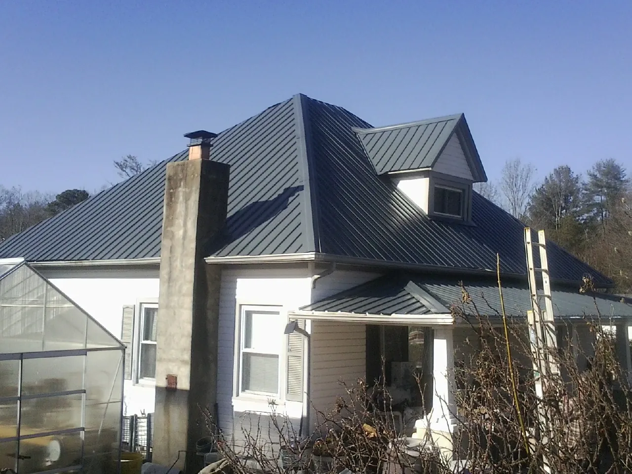 Dark blue standing seam metal roof on a white farmhouse with dormer — Slate & Tile Roof Repair by Roofing Brothers in Watervliet