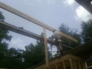 Carpenter setting a ridge beam over a new addition frame — Ice Dam Removal by Roofing Brothers in Watervliet