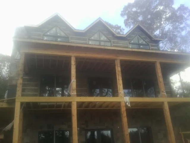 Dormers and porch framing on a large log home under construction — Roof Coating work by our crew in Watervliet