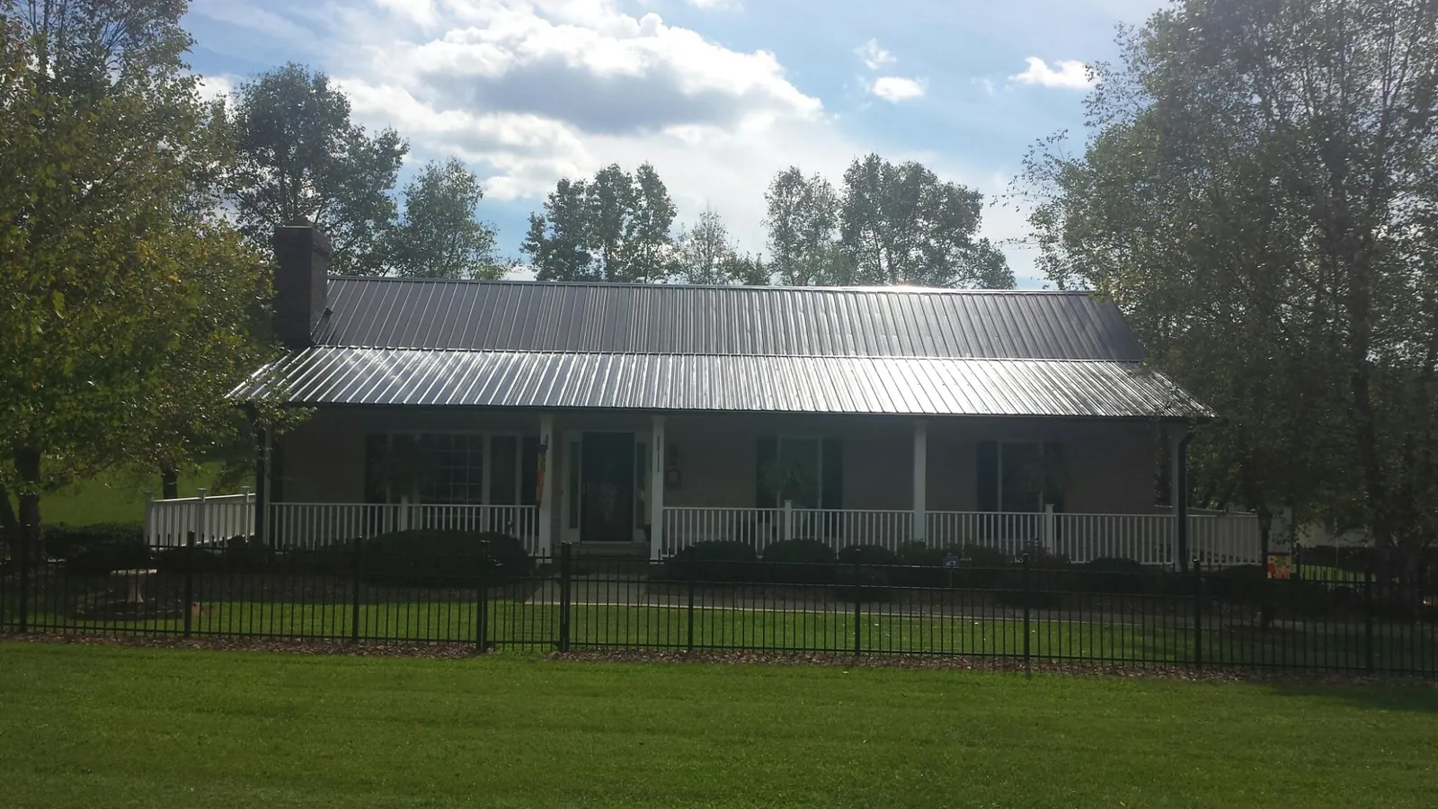 Gray metal roof on a brick ranch with a full width front porch — Gutter Guard Installation work by our crew in Watervliet