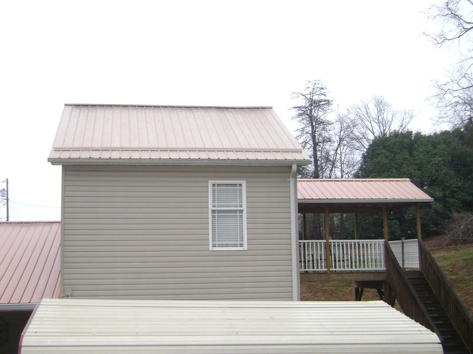 Tan metal roofs on a two story addition and attached porch, from a Roof Replacement job in Watervliet