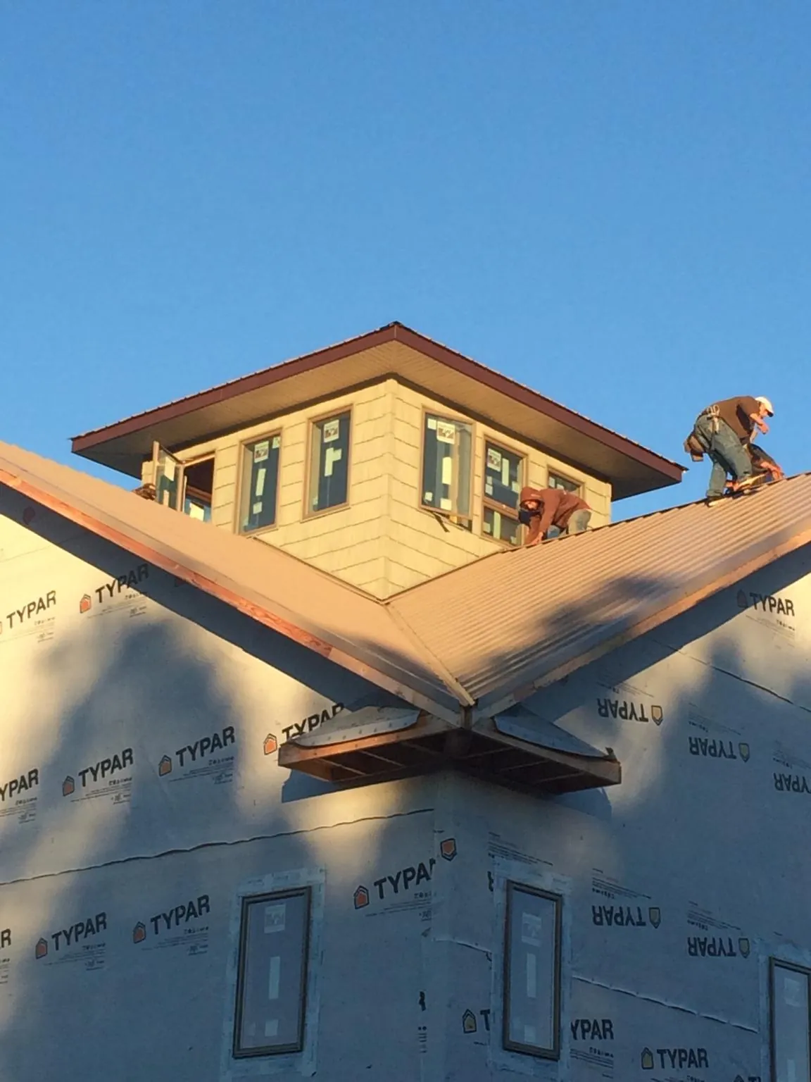 Roofers working around a rooftop cupola on a new metal roof at sunset — Roof Waterproofing in Watervliet by Roofing Brothers